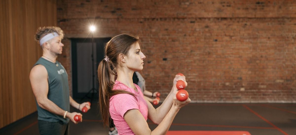 Group of adults exercising indoors with dumbbells, focused on fitness and health.
