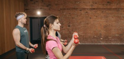 Group of adults exercising indoors with dumbbells, focused on fitness and health.