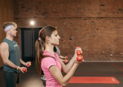 Group of adults exercising indoors with dumbbells, focused on fitness and health.